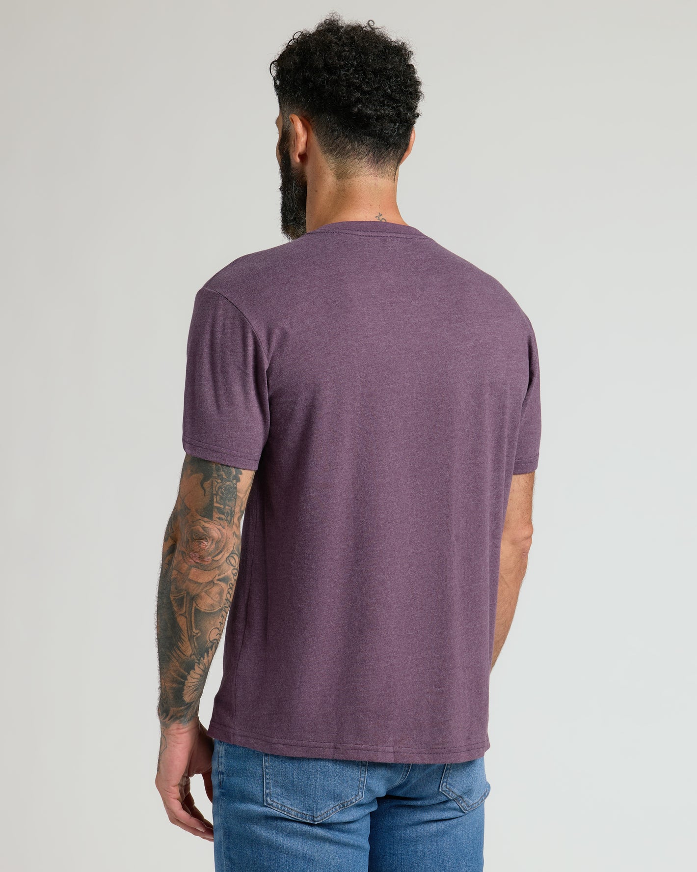 Man wearing Dark Heather Plum Classic V-Neck, showcasing tattoos.