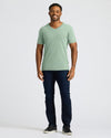 Man wearing a green t-shirt and dark jeans on a white background