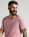 Man wearing Light Heather Boysenberry Classic V-Neck, smiling, showcasing tattoos.
