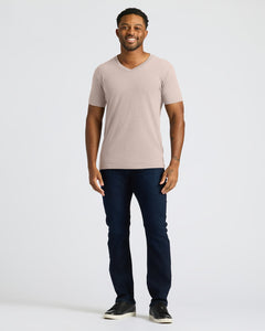 True ClassicMan wearing a beige t-shirt and dark jeans on a white background