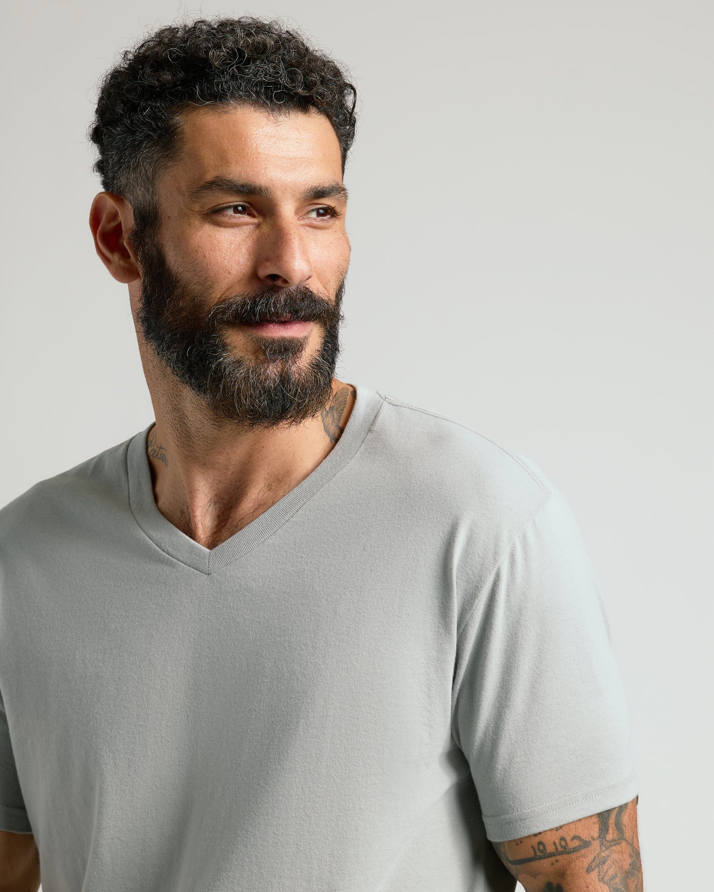 Steel Classic V-Neck worn by tattooed man with short curly hair.