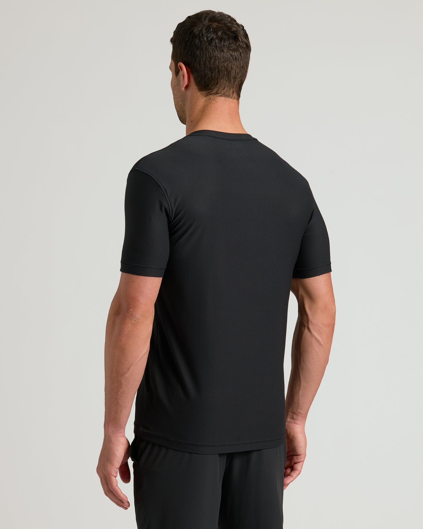 Man in Black Active V-Neck and shorts, back view.