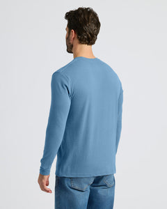 True ClassicA man shown from the back wearing a light blue long-sleeve crewneck shirt and blue jeans against a plain light gray studio background.