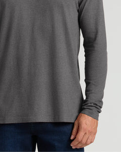 True ClassicA close-up of a person wearing a dark heather gray long-sleeve shirt with dark blue jeans, cropped from the chest down against a light gray background.