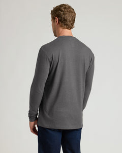 True ClassicA man viewed from the back wearing a dark gray long-sleeve crewneck shirt and dark blue jeans, standing against a light gray studio background.