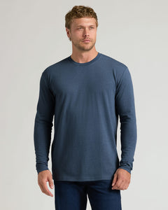 True ClassicA man wearing a slate blue long-sleeve crewneck t-shirt and dark blue jeans, standing against a light gray studio background.