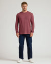 A man wearing a Dark Heather Rustic Apple Classic Long Sleeve Crew Neck shirt paired with dark jeans and white sneakers, standing against a plain light background.