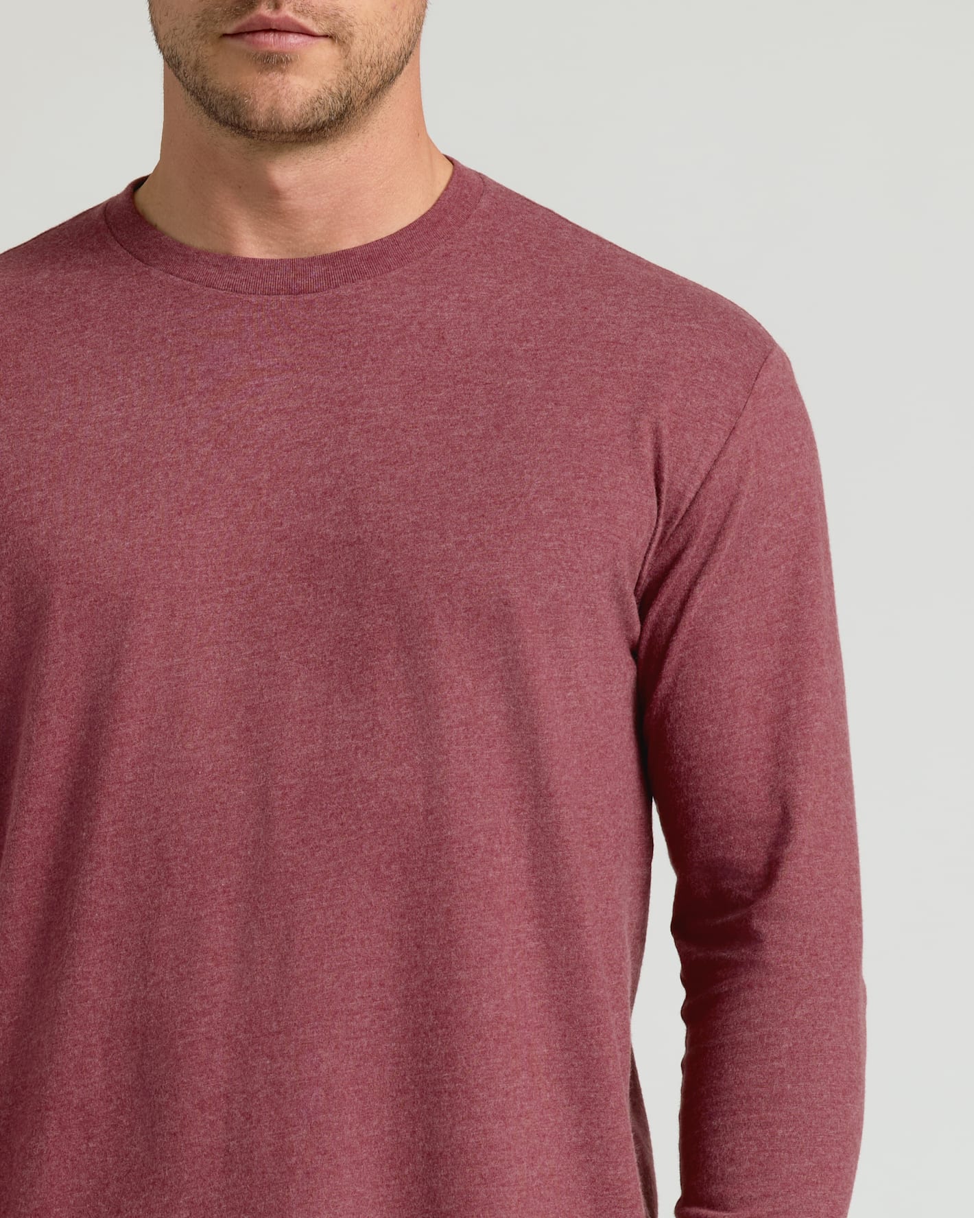 Close-up of a man wearing a Dark Heather Rustic Apple Classic Long Sleeve Crew Neck in a muted reddish-brown heathered fabric, showcasing the soft texture and simple crew neckline for men's basics.