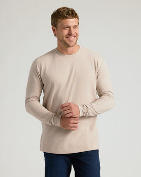 Man in beige Seasonal Classic Long Sleeve Crew, adjusting sleeve, jeans.