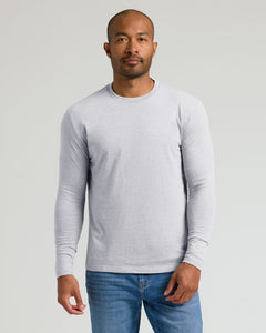 True ClassicA man wearing a light gray long-sleeve crewneck shirt and blue jeans, standing against a solid light gray background.