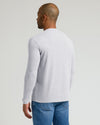 A man shown from the back wearing a light gray long-sleeve crewneck shirt and blue jeans, photographed against a solid light gray studio background.