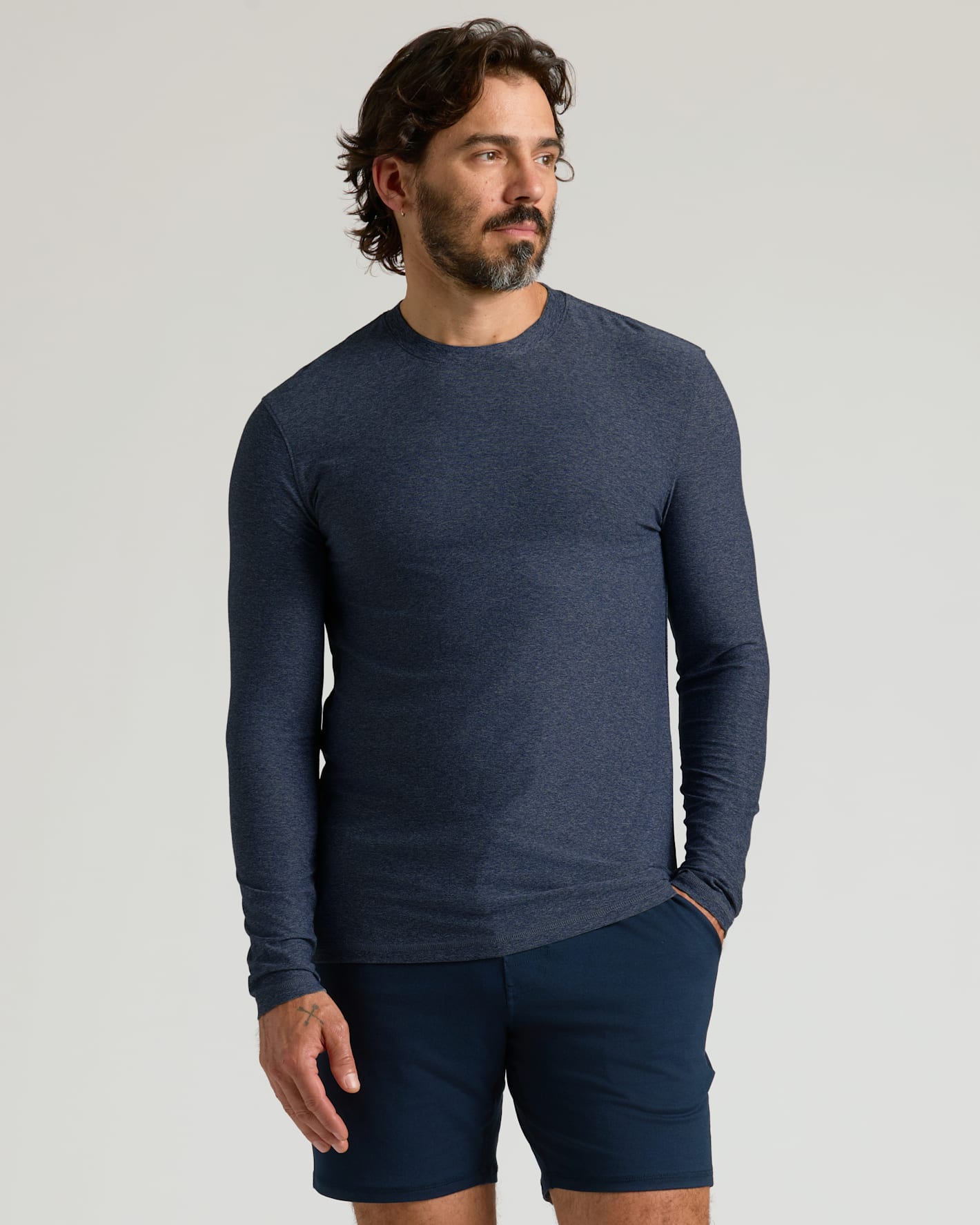 Man wearing a Dark Heather Fiord Active Long Sleeve Crew T-Shirt with navy shorts, posing against a plain light background in a casual style.