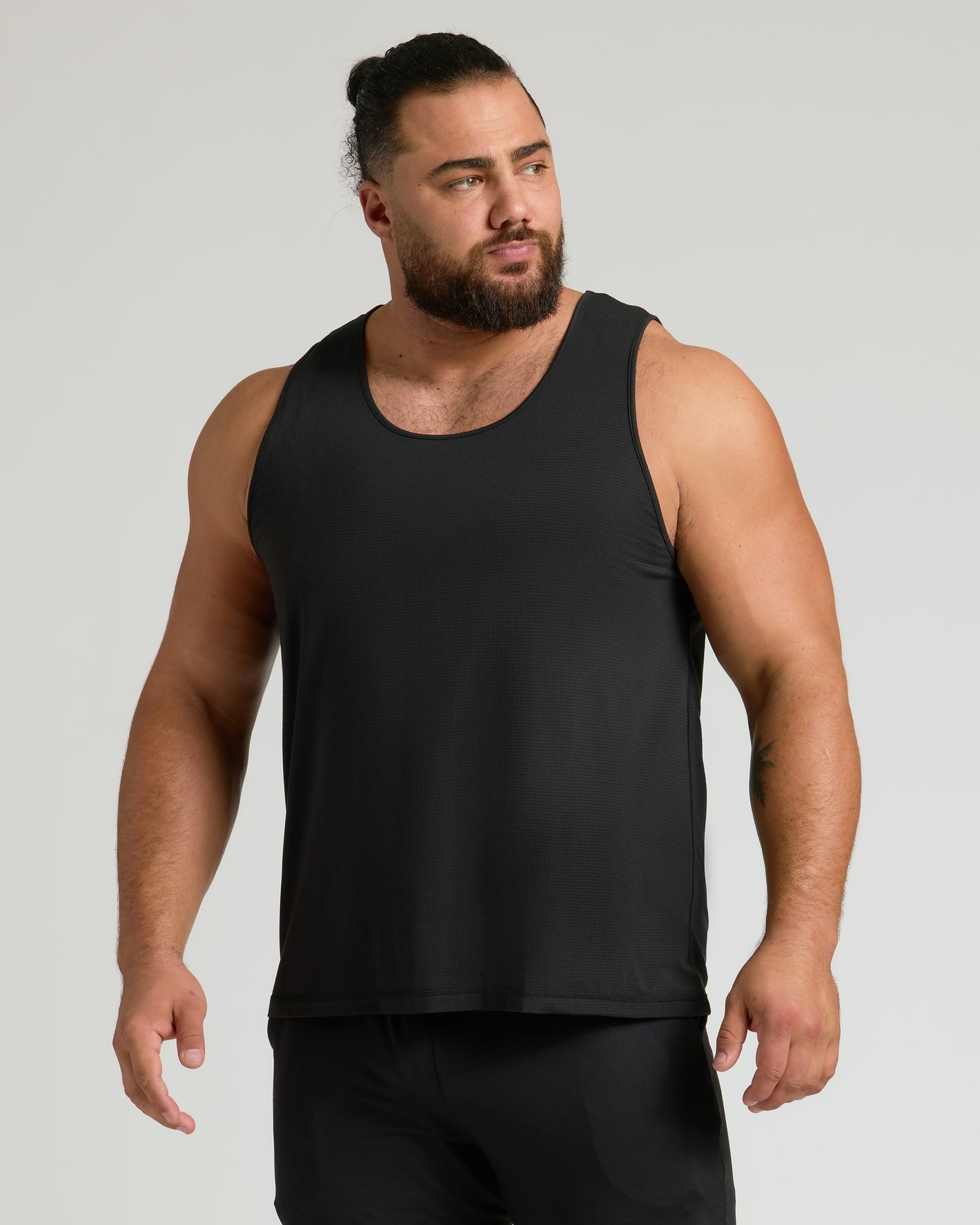 Man wearing The Staple Sleeveless Active Mesh Tank 3-Pack.