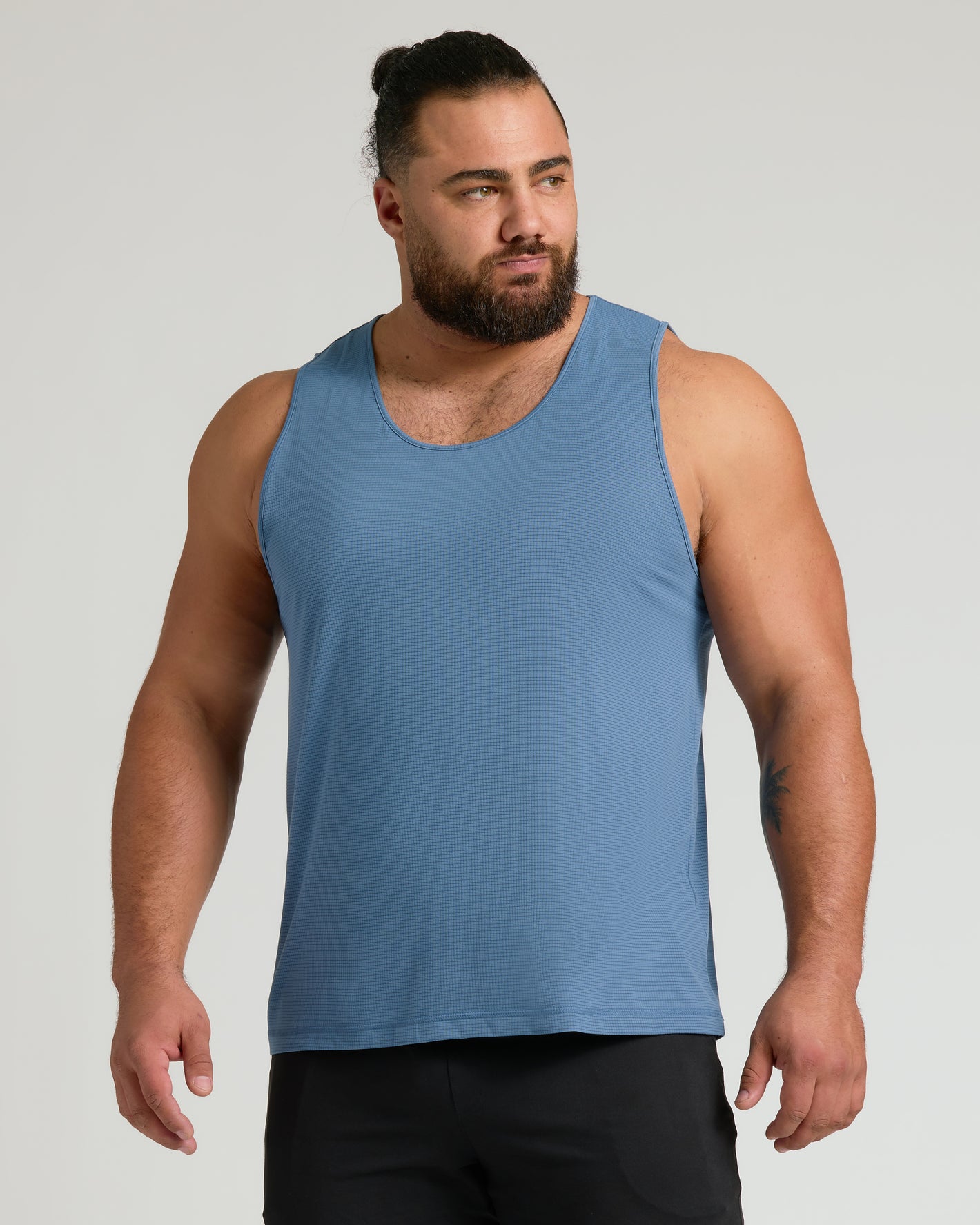 Muscular man in The Staple Sleeveless Active Mesh Tank 3-Pack.