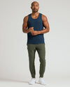 Man wearing Sleeveless Active Mesh Tank, navy, with olive joggers and white trainers.