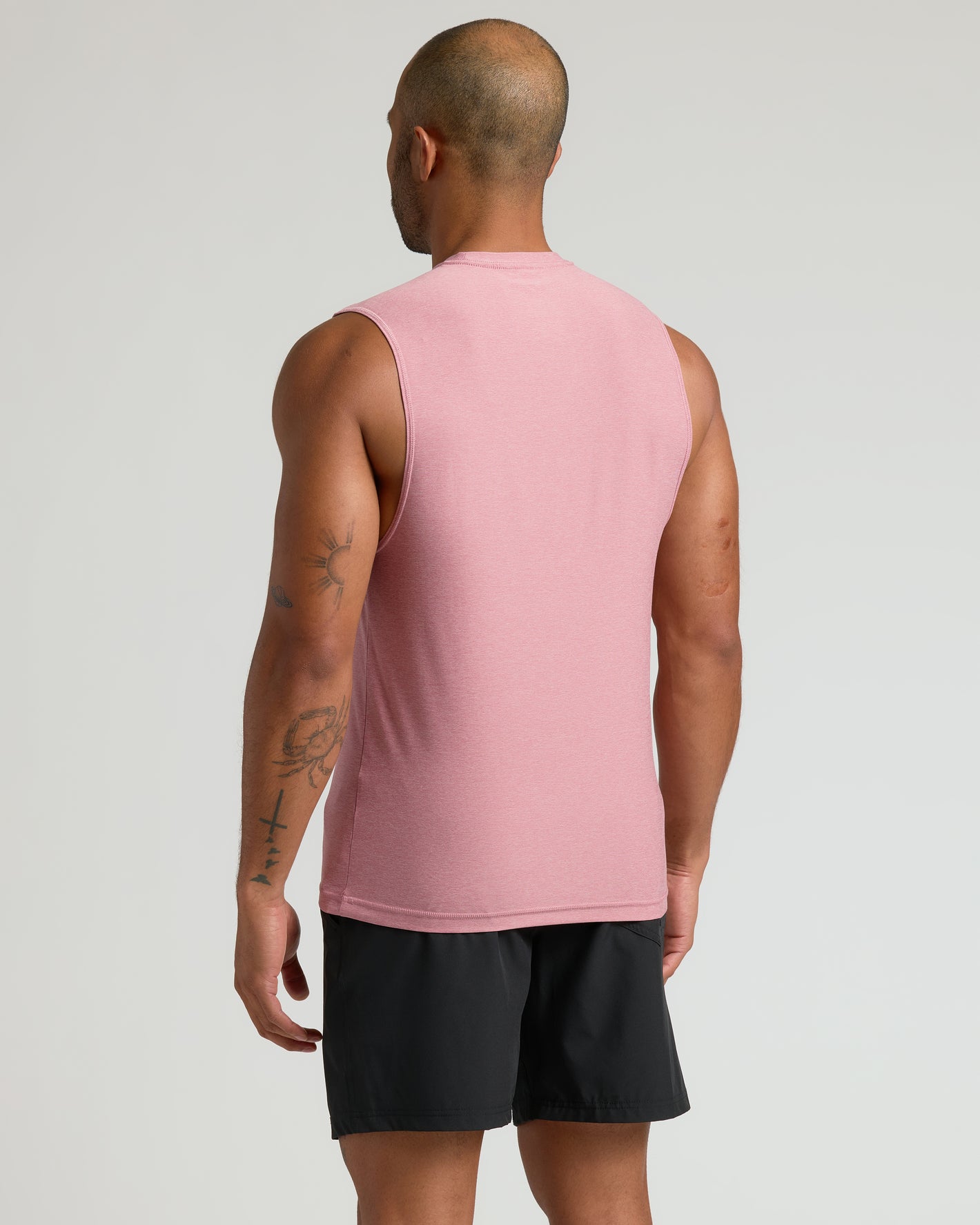 Man wearing Quartz Rose Sleeveless Active Muscle Tee, showcasing back and tattoos.