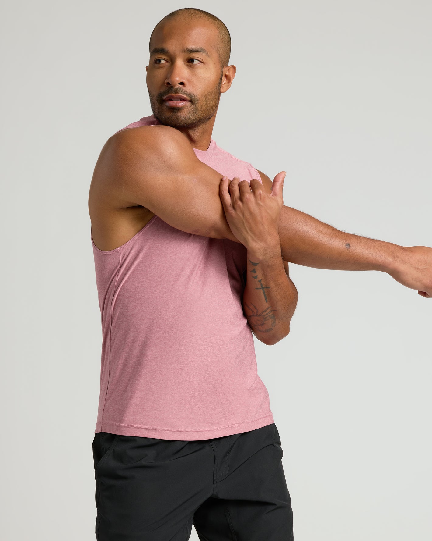 Man stretching in Quartz Rose Sleeveless Active Muscle Tee.