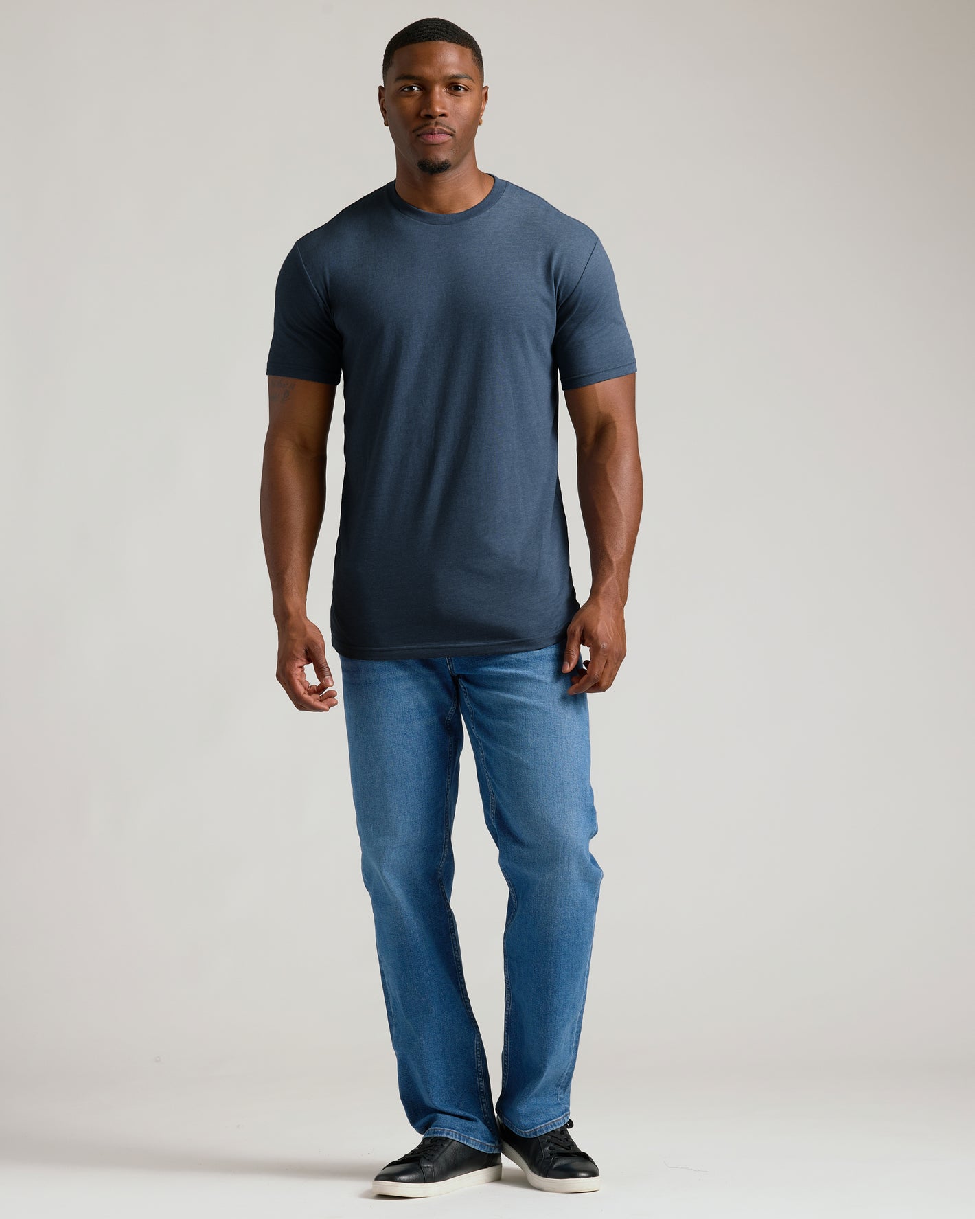 Man wearing Heather Navy Tall Straight Hem Crew Neck T-Shirt, jeans, sneakers.