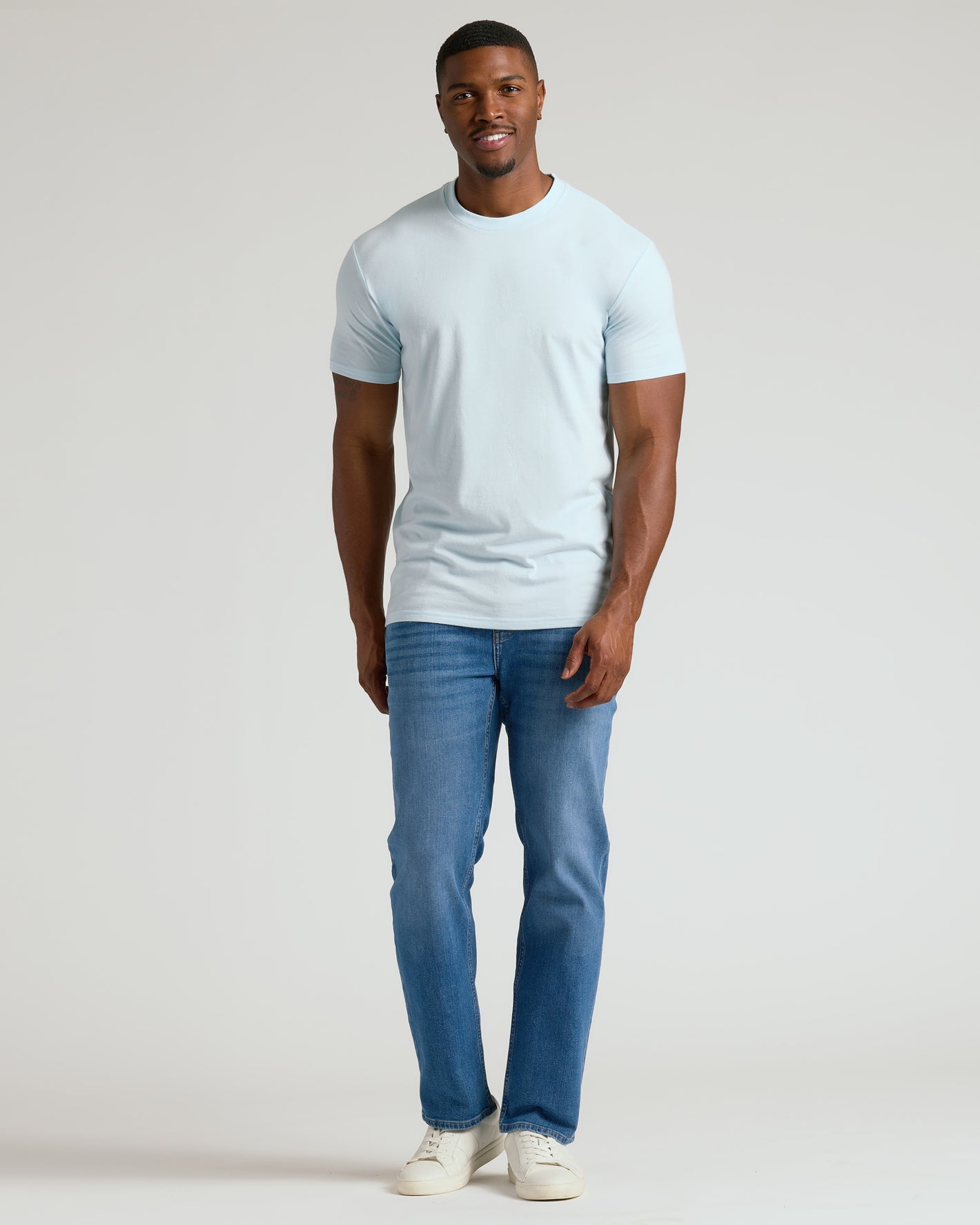 Man wearing Icicle Tall Straight Hem Crew Neck T-Shirt, jeans, sneakers.