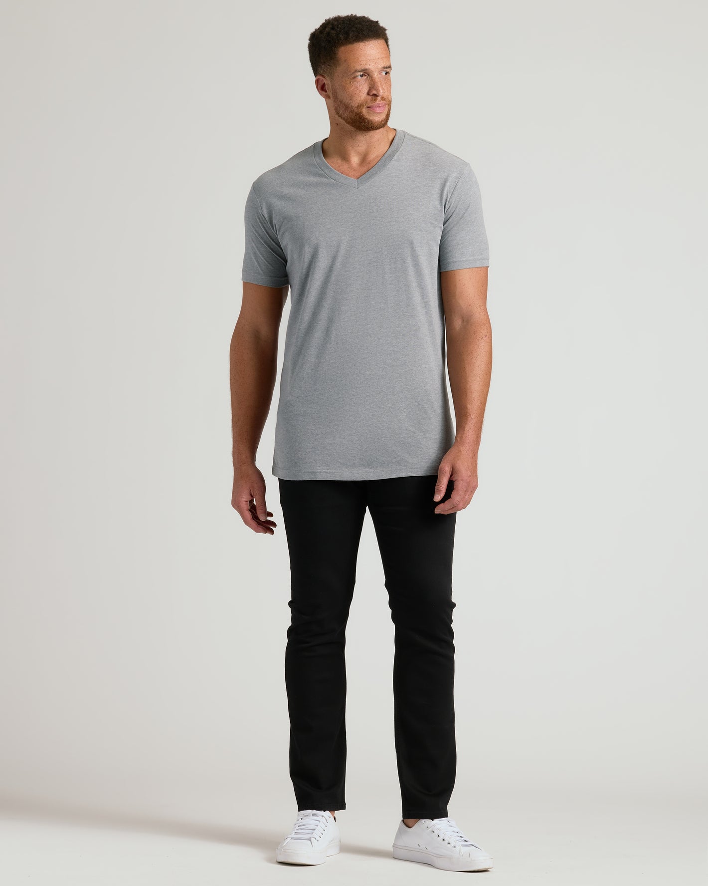 Man in Heather Gray Tall Short Sleeve Classic V-Neck, slim-fit pants, sneakers.