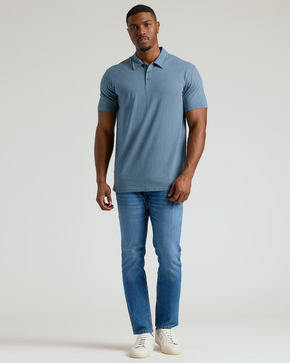 Man wearing Dark Heather Tempest Short Sleeve Tall Polo with jeans and sneakers.