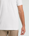 Close-up of a person wearing a plain white short-sleeve T-shirt with beige pants, shown against a light gray studio background.