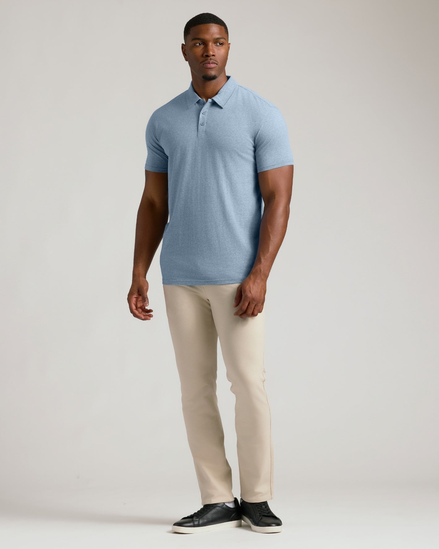 Model wearing Heather Indigo Short Sleeve Tall Polo with beige trousers.