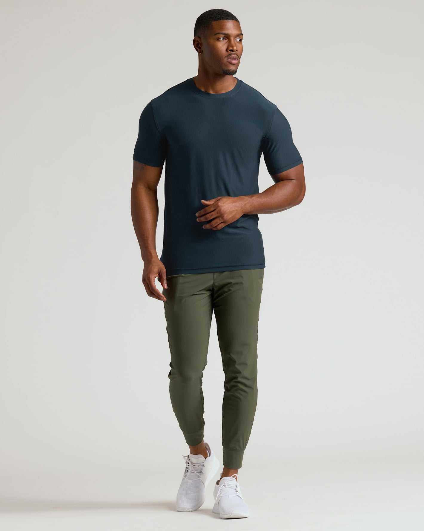 Man wearing a dark green t-shirt and olive green pants on a white background