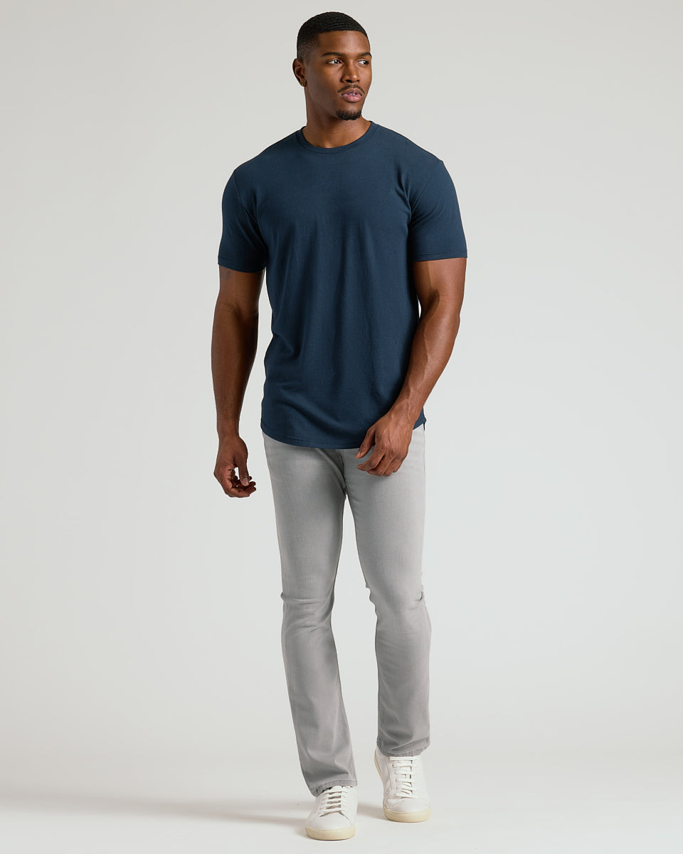 Man in Navy Short Sleeve Tall Curved Hem Crew, slim-fit jeans, sneakers.