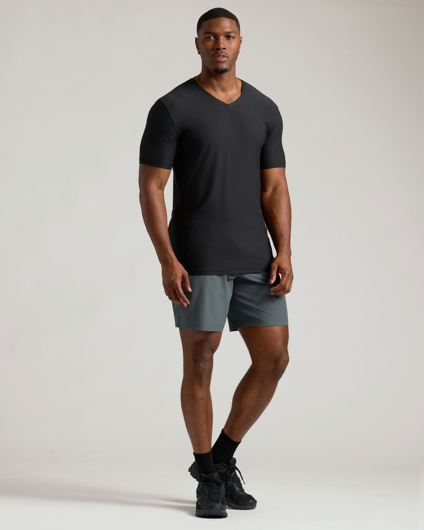 Man wearing a black t-shirt and gray shorts on a plain background