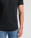 Close-up of a man wearing a black Tall Pima Cotton Blend Curved Hem Crew 7-Pack t-shirt paired with blue jeans, highlighting the smooth fabric and curved hem detail.