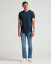 Man wearing a navy crew neck t-shirt with curved hem paired with light blue jeans and white sneakers, showcasing the Tall Pima Cotton Blend Curved Hem Crew 4-Pack in a casual style.