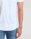 Close-up of a man wearing a white Tall Pima Cotton Blend Curved Hem Crew 7-Pack shirt paired with blue jeans, showcasing the curved hem detail and smooth cotton blend fabric.