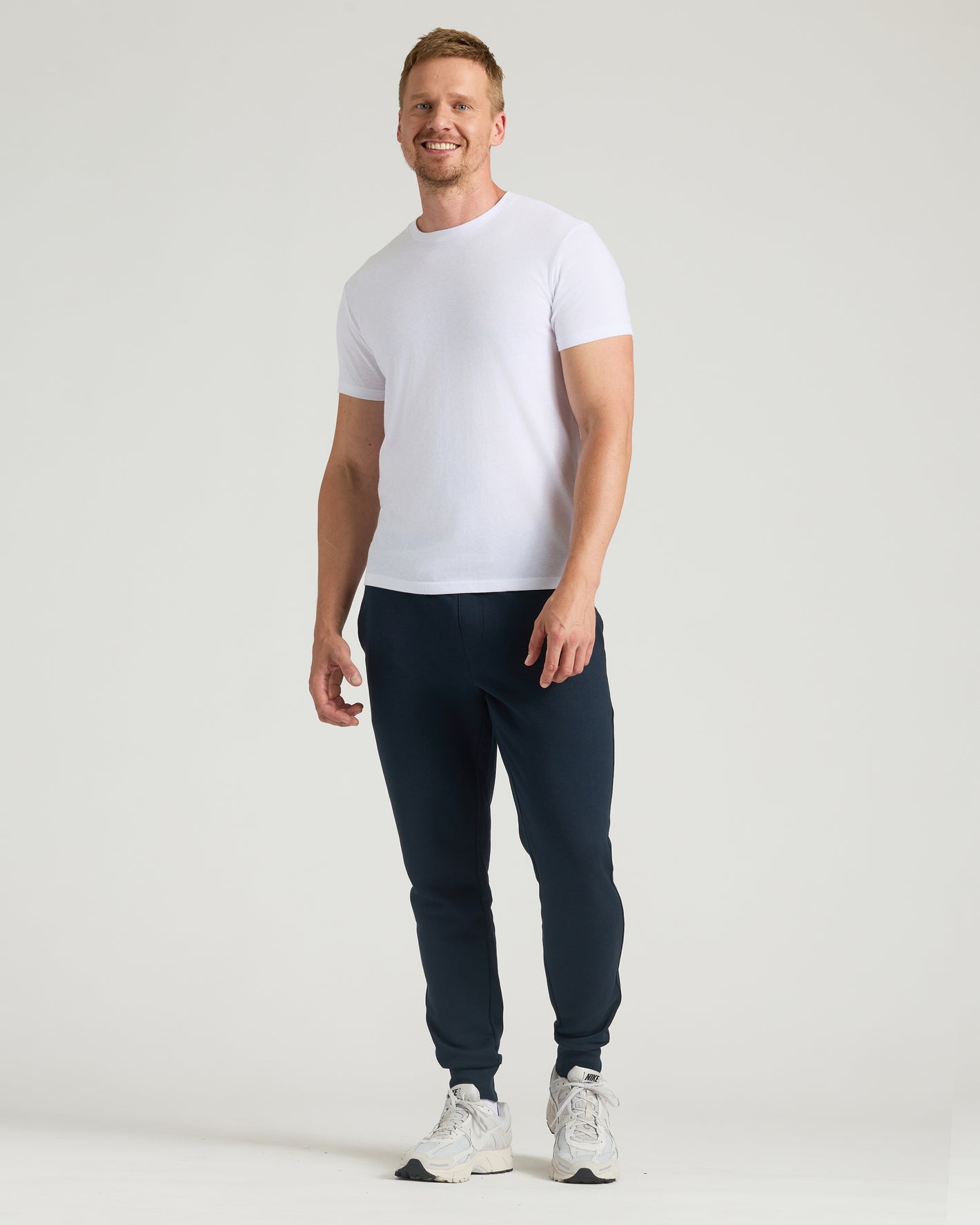 Man wearing Navy Tall Fleece French Terry Joggers with white sneakers.