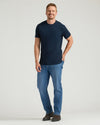 Man wearing a navy t-shirt and blue jeans on a white background