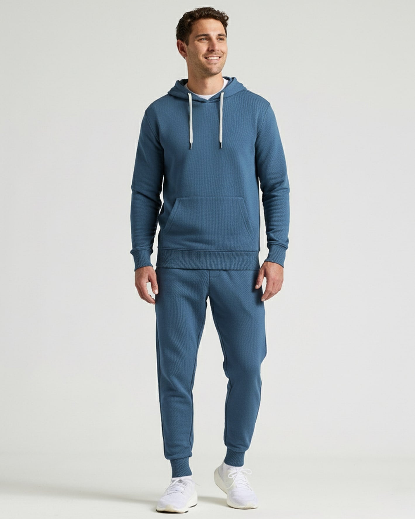 Man wearing a blue Fiord Fleece French Terry Pullover Hoodie paired with matching jogger pants and white sneakers, standing against a plain background.