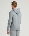 Man wearing a Dark Heather Gray Fleece French Terry Pullover Hoodie viewed from the back, showcasing a comfortable fit and hood detail in a casual setting.