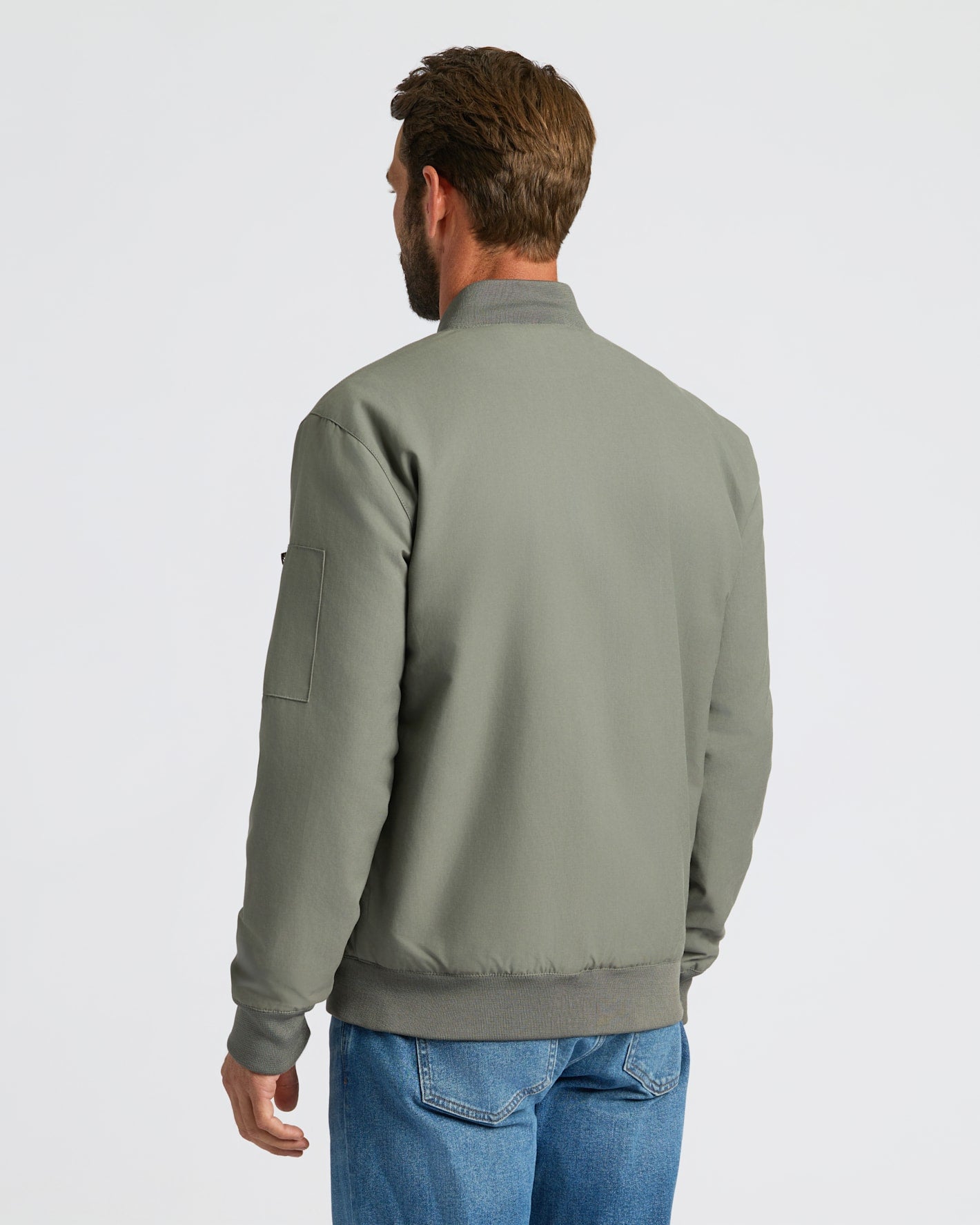 Man wearing Carbon Bomber Jacket with jeans, viewed from behind.