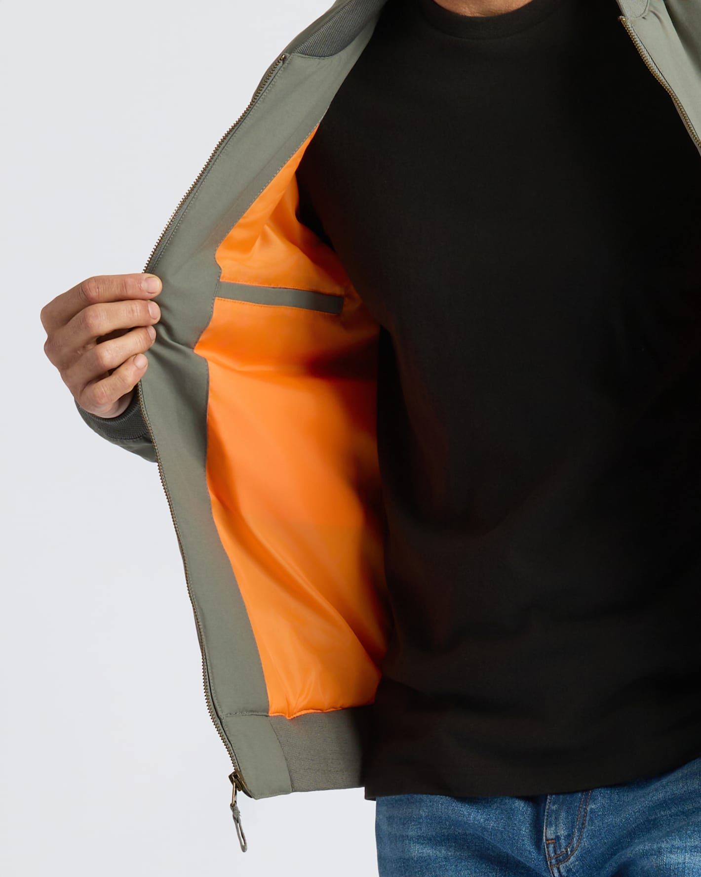 Person wearing Black & Carbon Bomber Jacket, showing orange lining and interior pocket.