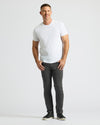 Man wearing a white t-shirt and black jeans on a light gray background