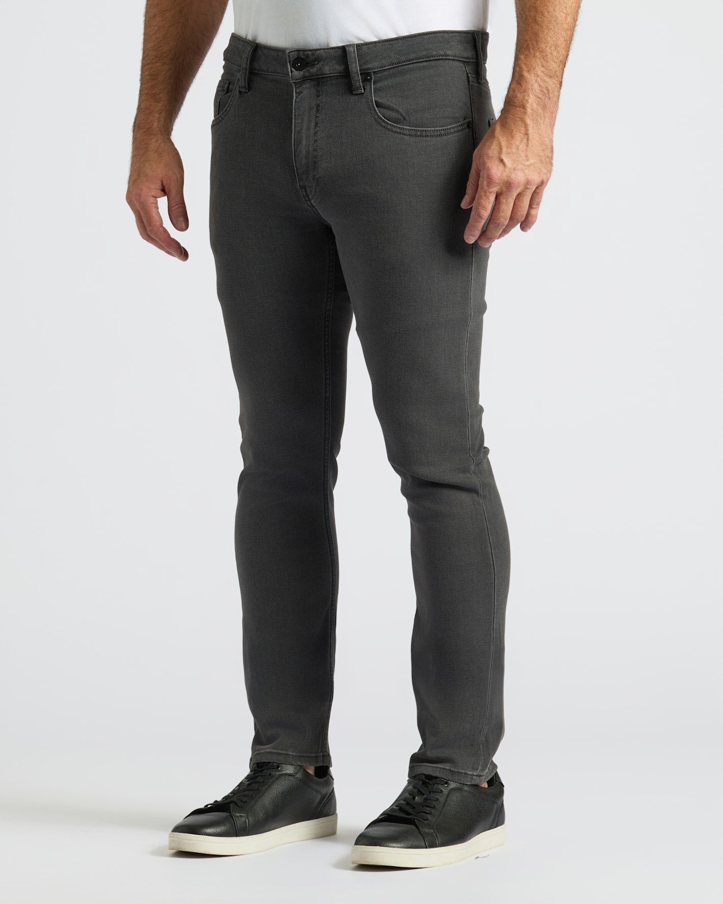 Person wearing dark gray jeans on a white background