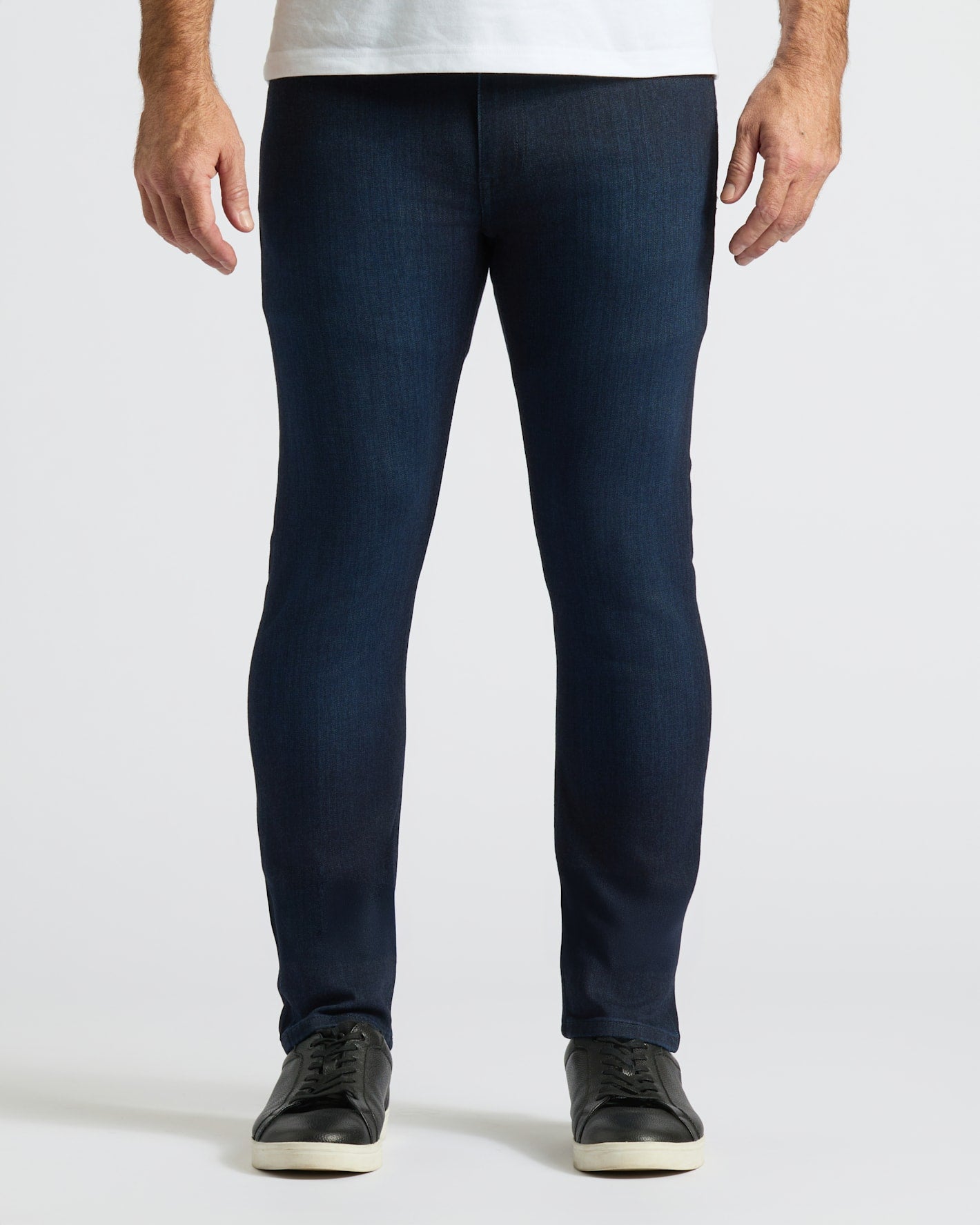 Person wearing dark blue jeans on a white background