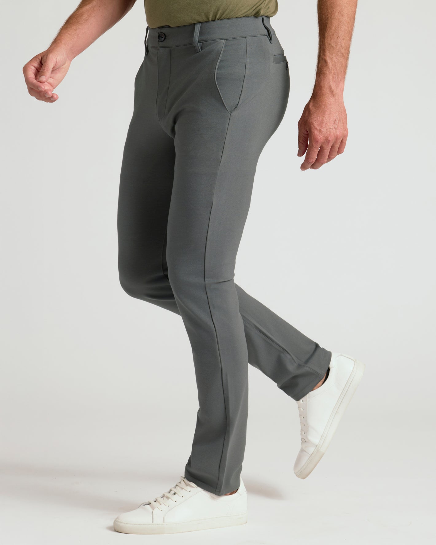 Person wearing gray pants and white sneakers on a white background