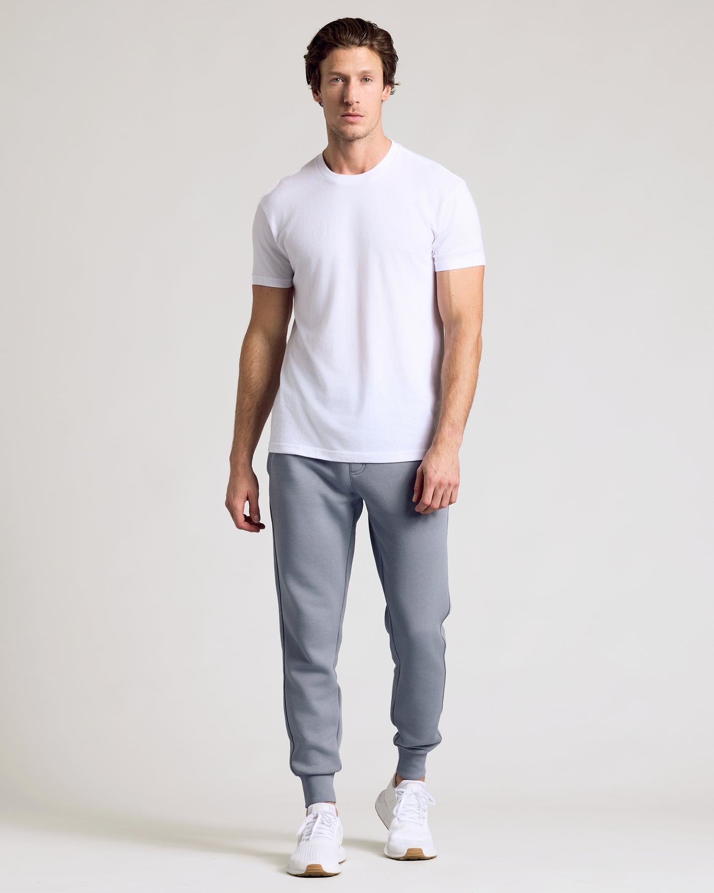 Man wearing Dusty Blue Fleece French Terry Joggers with white T-shirt and sneakers.