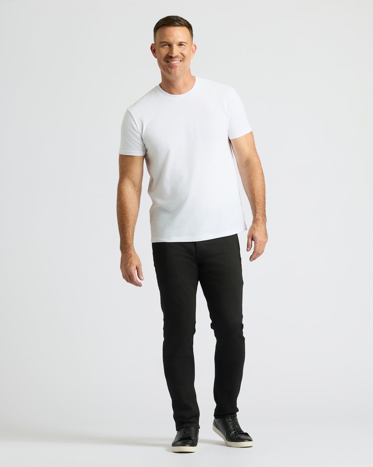 Man wearing a white t-shirt and black pants on a white background