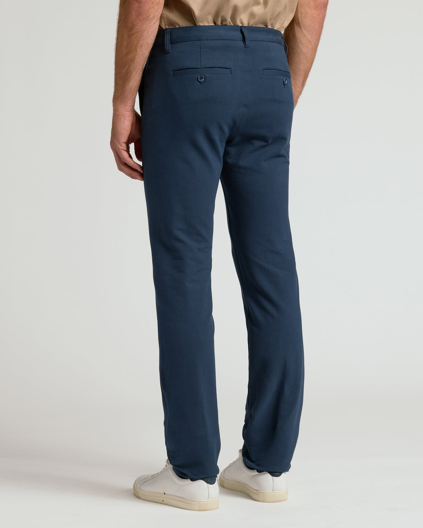 Navy Slim Chino Pants 2.0 back view, paired with white sneakers.