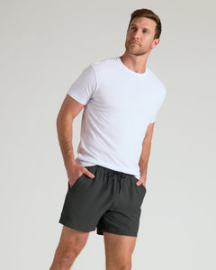 True ClassicYoung man in 5 Smoke Seersucker Swim Trunks, hands in pockets.