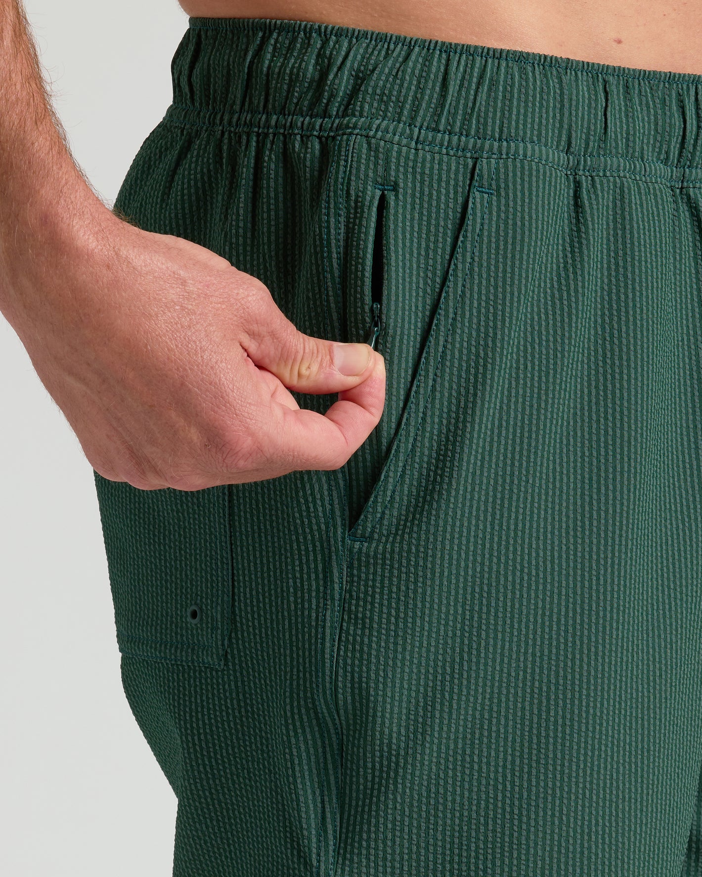 Hand unzipping pocket on 7 Marine Spruce Seersucker Swim Trunks.