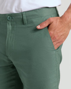 True Classic7 Moss Linen Shorts with waistband, button, and hand in pocket.