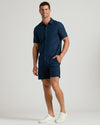 Man wearing 7 Navy Linen Shorts with a matching shirt and sneakers.